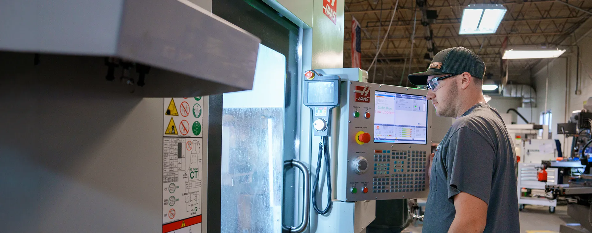 Operator using CNC machine control panel with screen and buttons in workshop